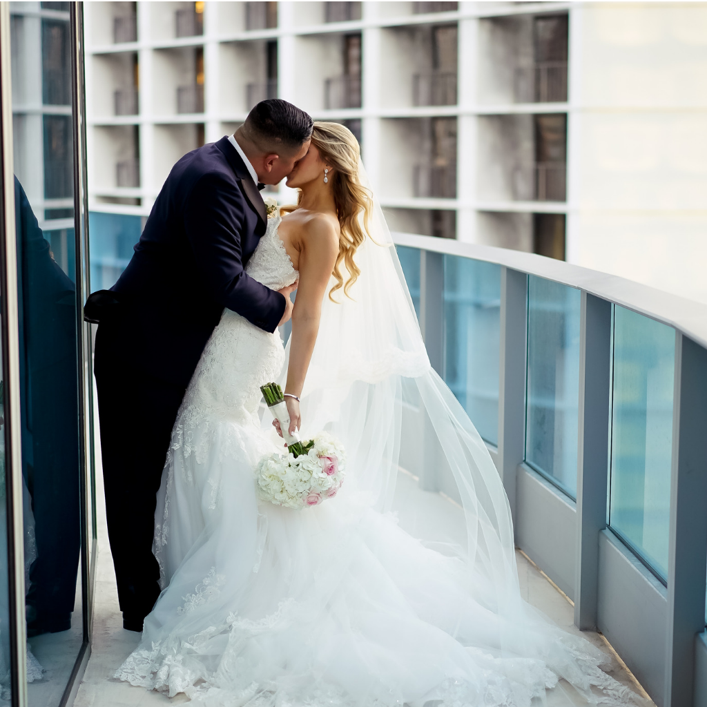 bride and groom kiss on the ballroom terrace of epic hotel