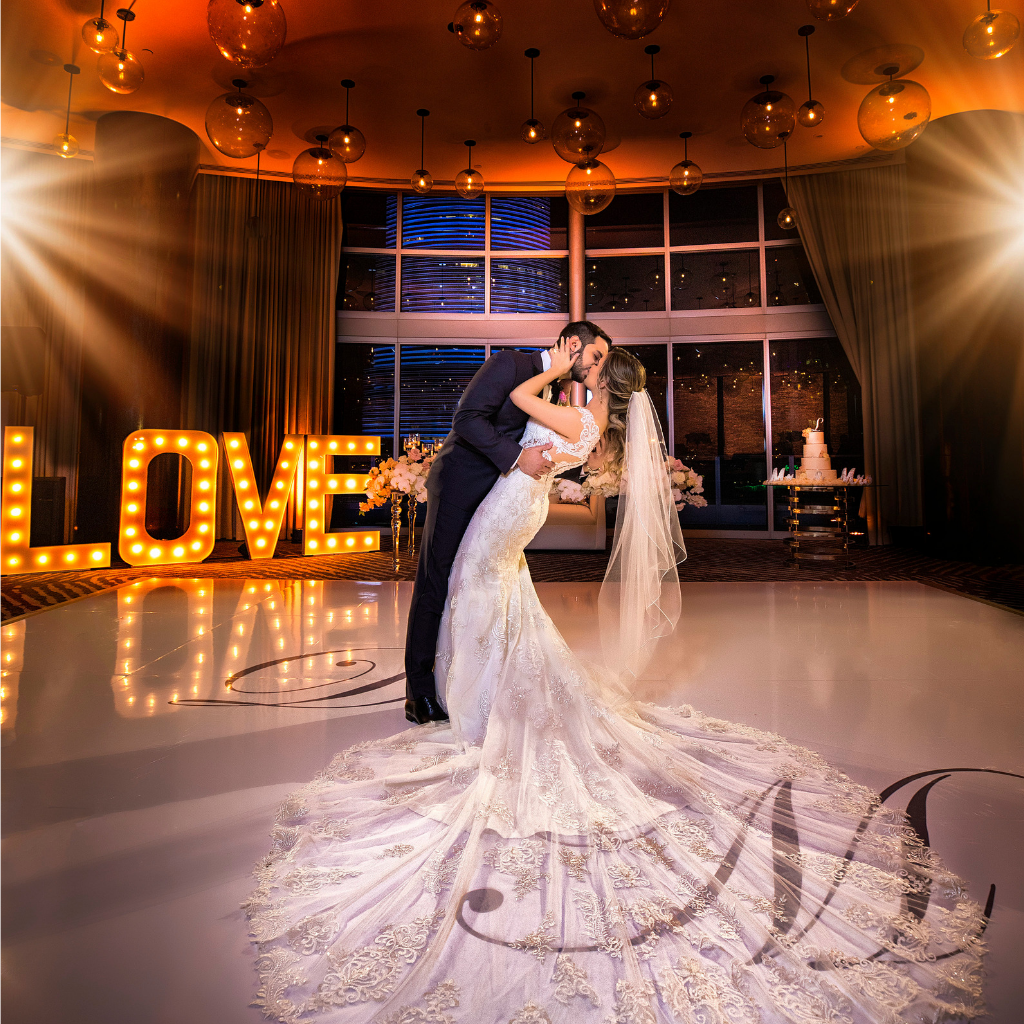 bride and groom kiss in front of a love marquee in the epic hotel ballroom