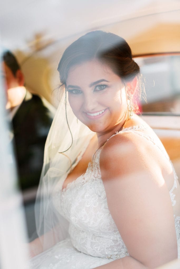 The bride peeks out the car window as they make their getaway