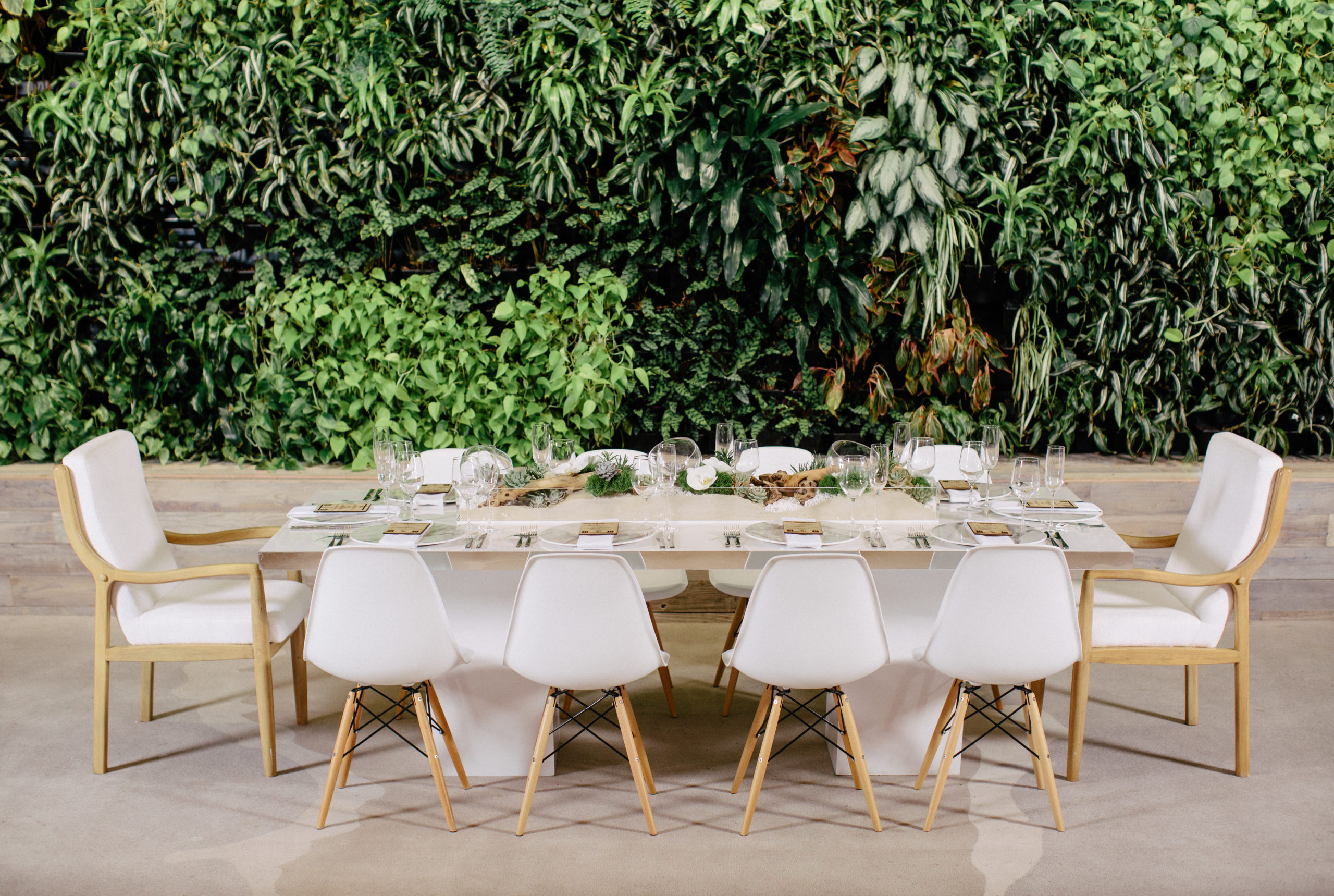 Acrylic wedding table with white wood dowel chairs and statement chairs at either end, featuring marble charger plates and resin name plates that served as unique place cards with a wood engraved menu buckle