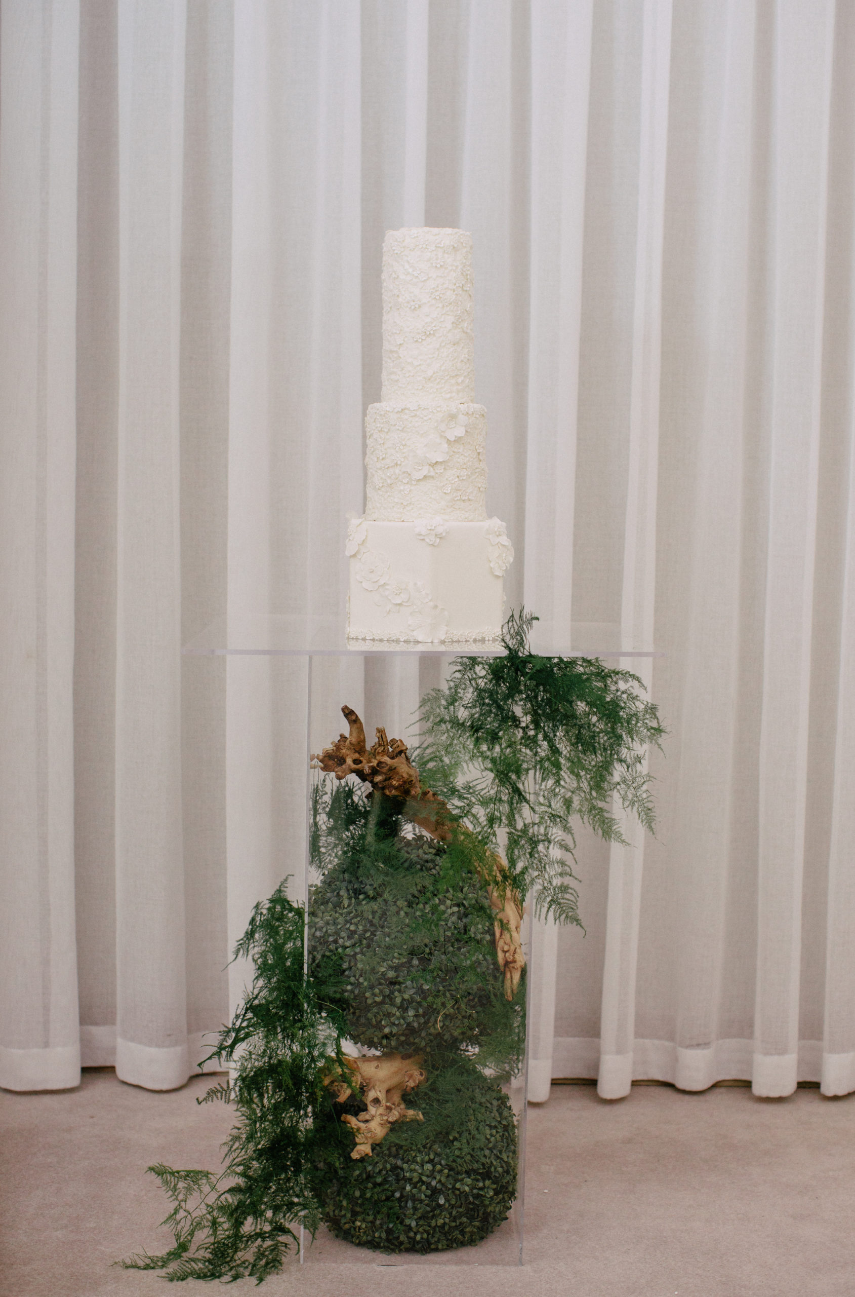 A terrarium cake stand and greenery compliments the Sweet Guilt by Angelica fondant wedding cake