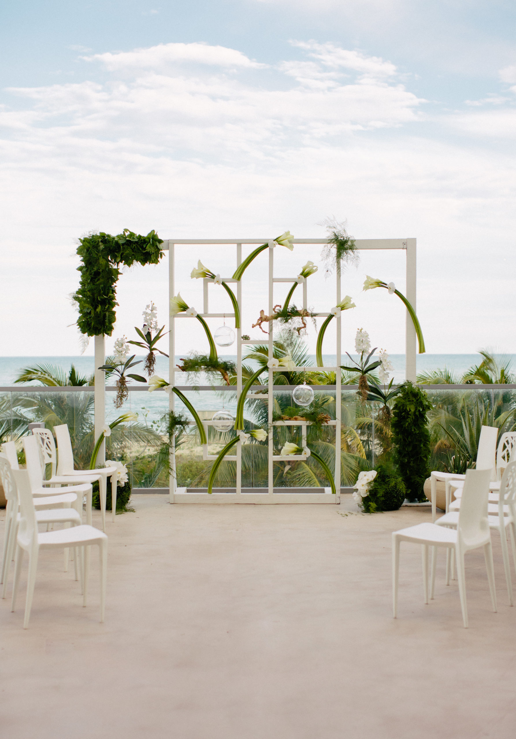 A Unique ceremony setup placed guest chairs around the couple to form an open circle encasing the couple and showcasing the custom ceremony structure with calla lilies, orchids, and greenery at the 1 Hotel South Beach