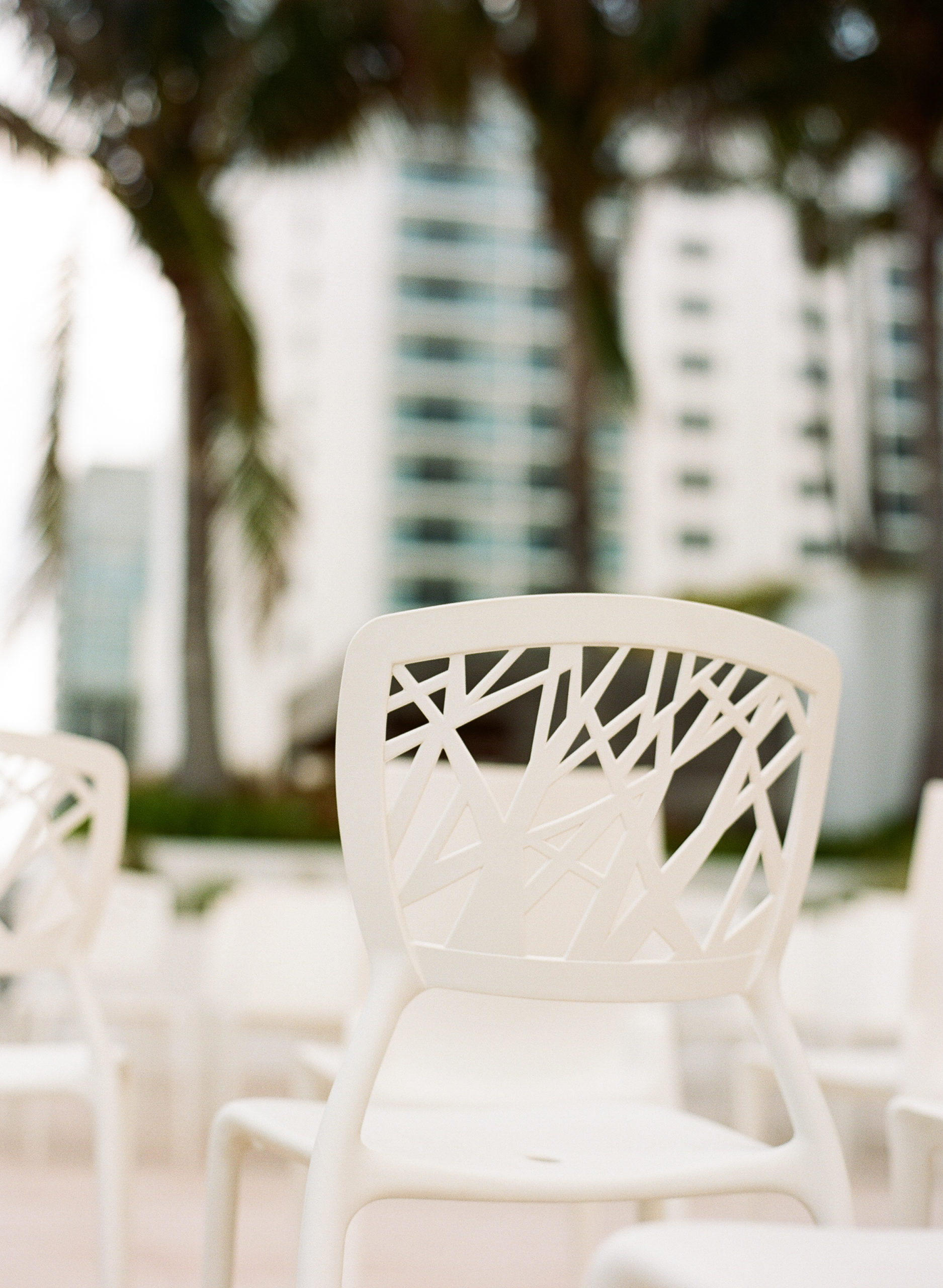 A Unique ceremony setup placed guest chairs around the couple to form an open circle encasing the couple and showcasing the custom ceremony structure with calla lilies, orchids, and greenery at the 1 Hotel South Beach using Twig chairs from Lavish event rentals