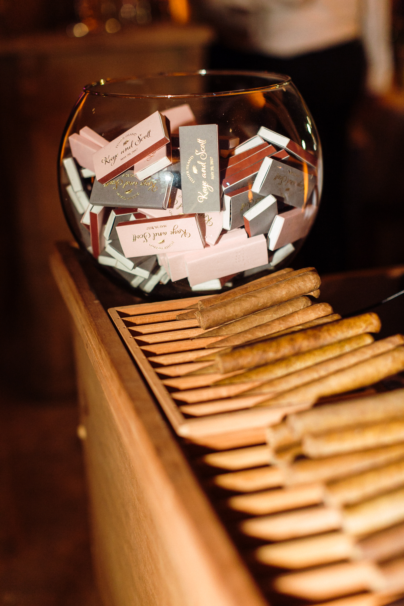 Custom match boxes with the couple's logo, names, and wedding date in gold foil were placed in a giant fish bowl next to the cigar roller