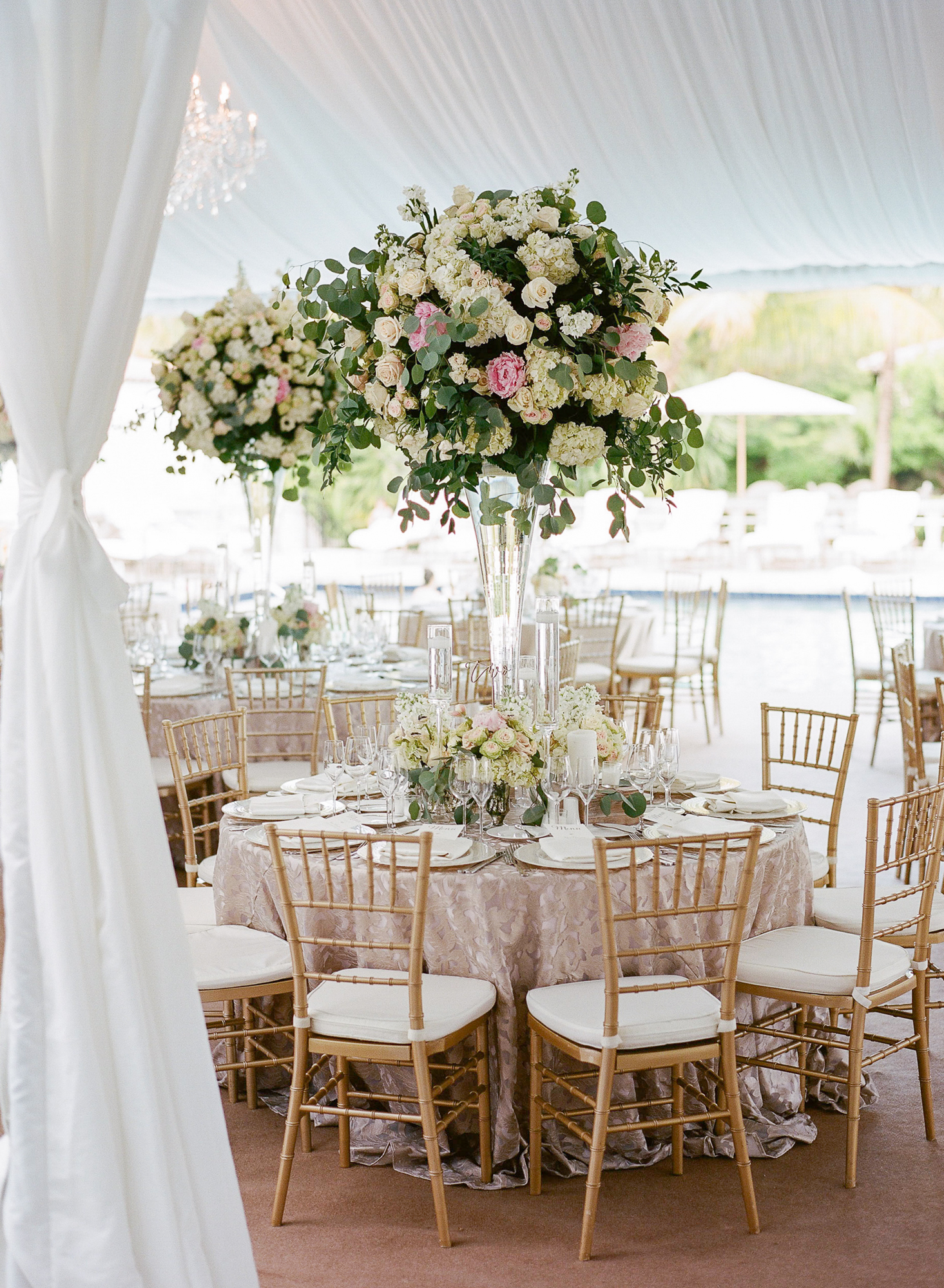 The fisher island club terrace was carpeted and featured a mix of long royal tables and round guest tables. The centerpieces used eucalyptus and wood boxes for a very French feel. Glass vases added a clean and modern touch | fisher island club, fisher island wedding, south florida wedding planner, florida wedding