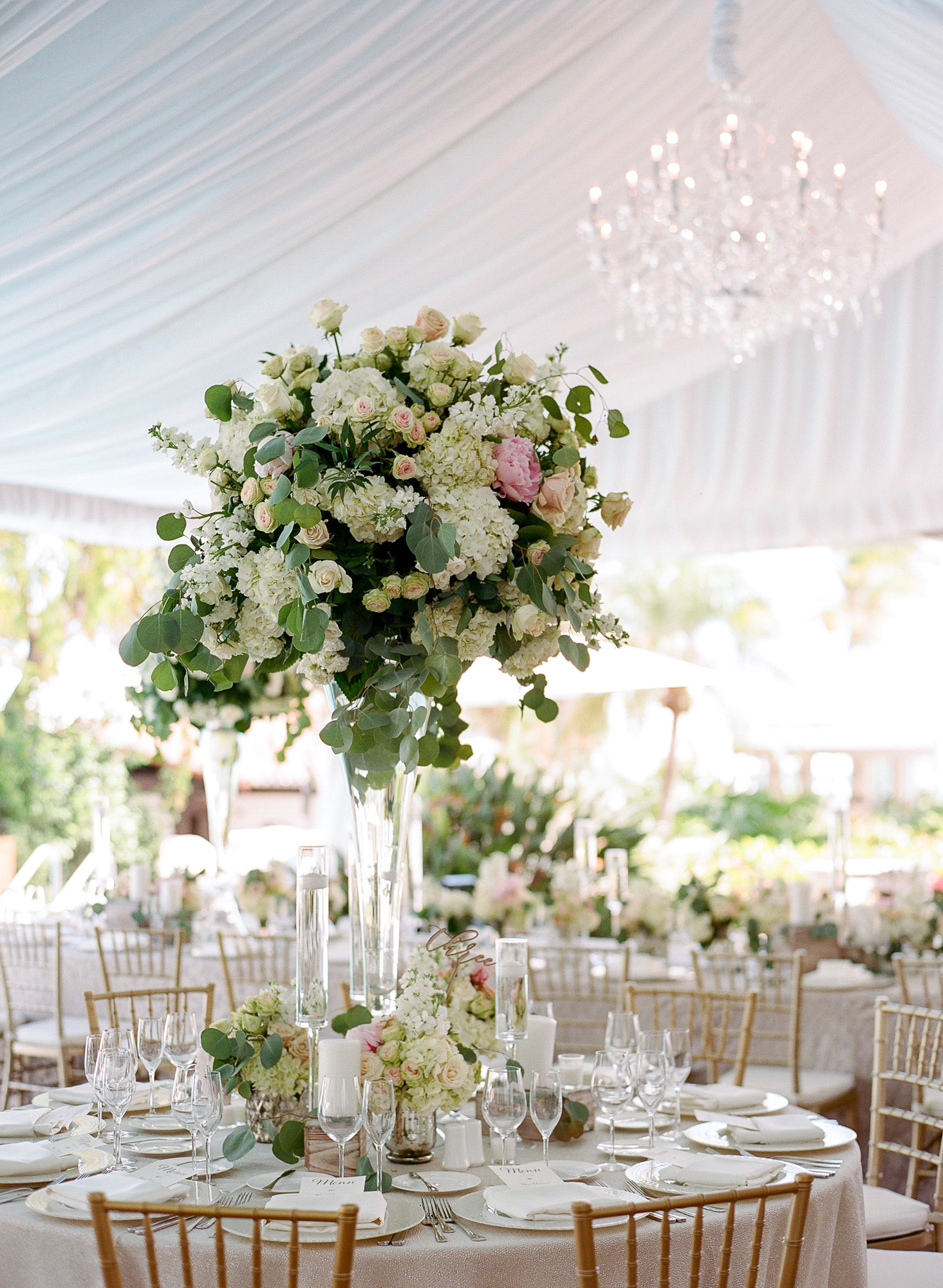 The fisher island club terrace was carpeted and featured a mix of long royal tables and round guest tables. The centerpieces used eucalyptus and wood boxes for a very French feel. Glass vases added a clean and modern touch | fisher island club, fisher island wedding, south florida wedding planner, florida wedding