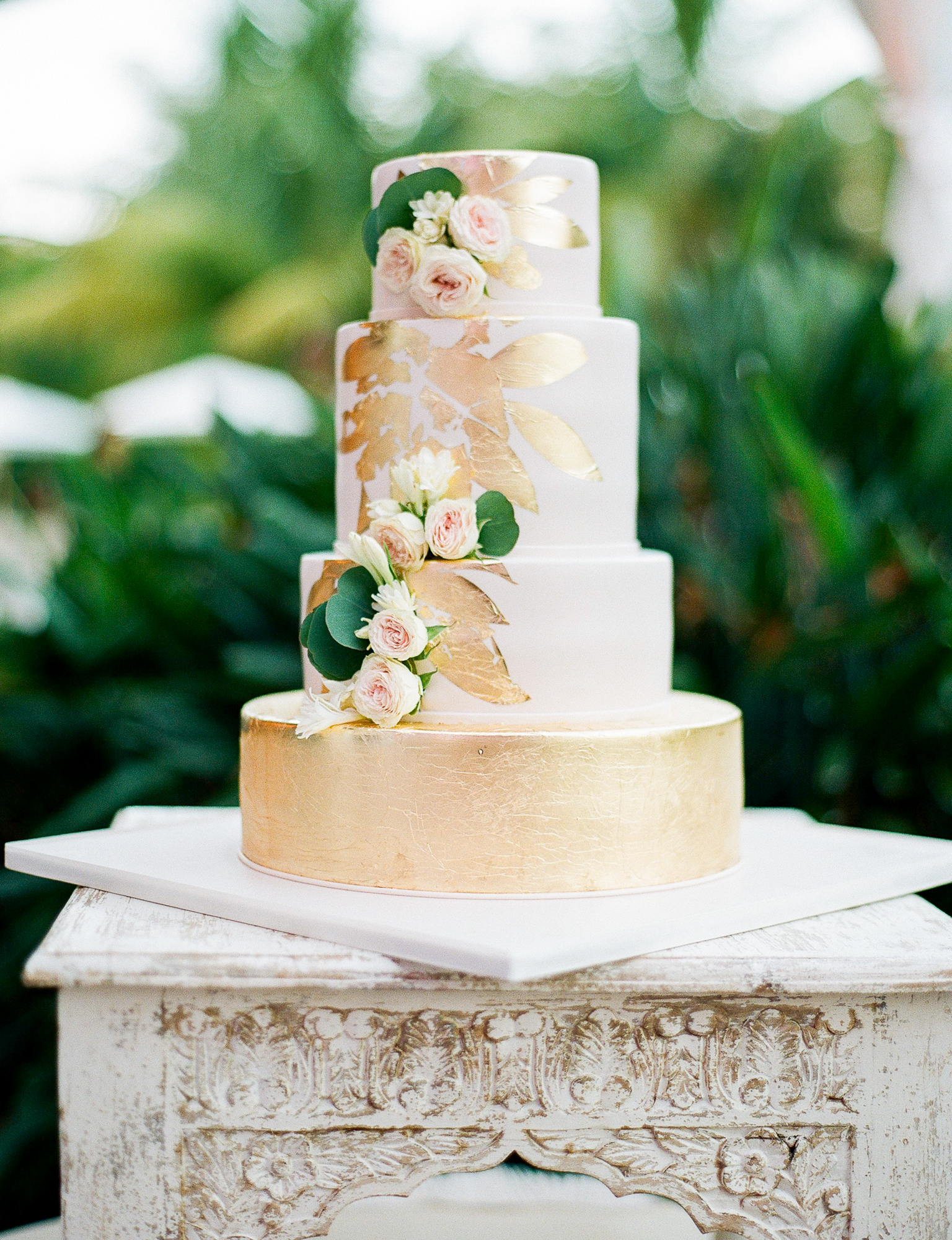 Pink and gold wedding cake. This cake was designed by Elegant Temptations and featured blush fondant, edible gold foil, and real flowers. Guests enjoyed the vanilla rum and coconut flavors