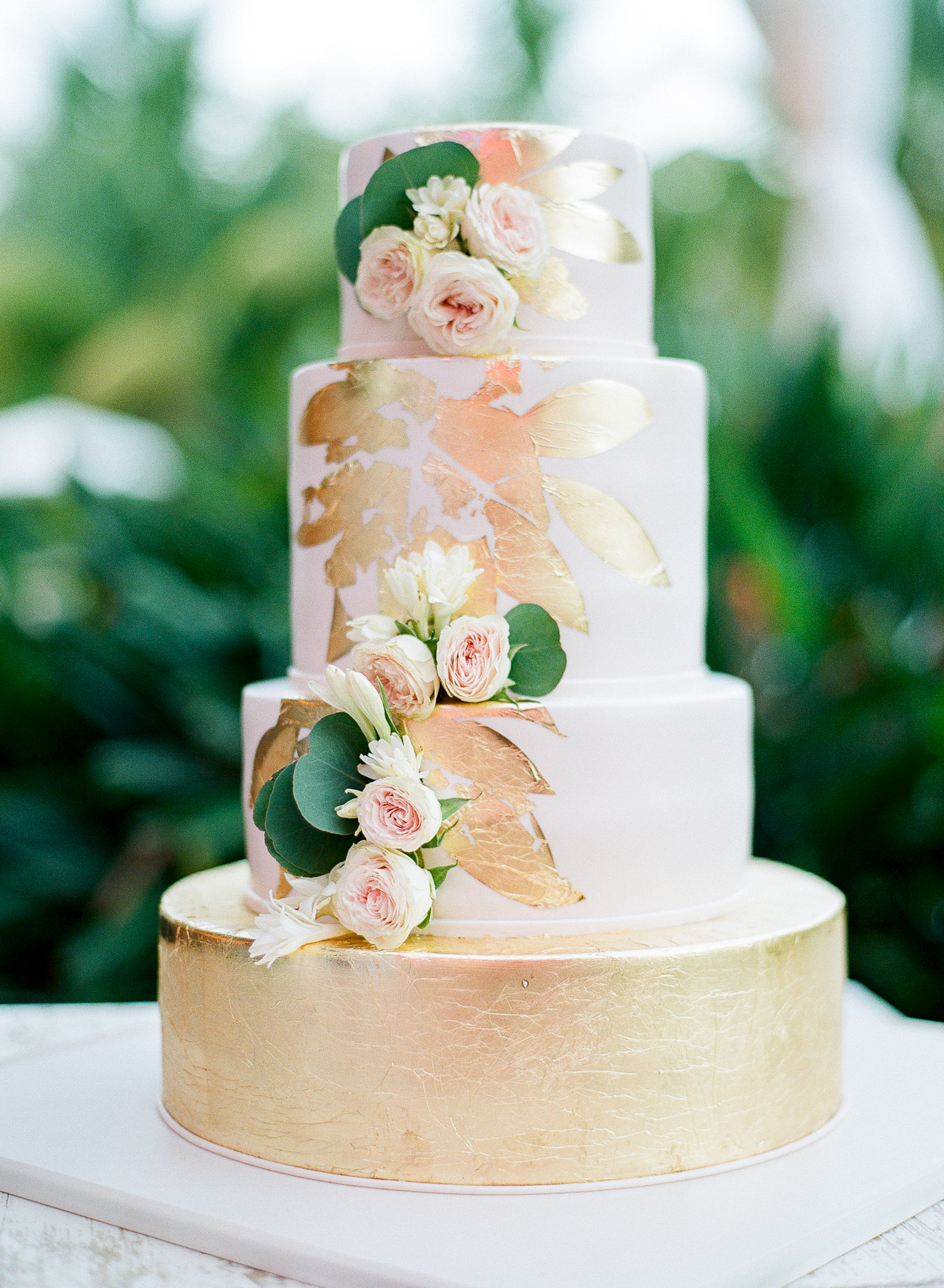 Pink and gold wedding cake. This cake was designed by Elegant Temptations and featured blush fondant, edible gold foil, and real flowers. Guests enjoyed the vanilla rum and coconut flavors