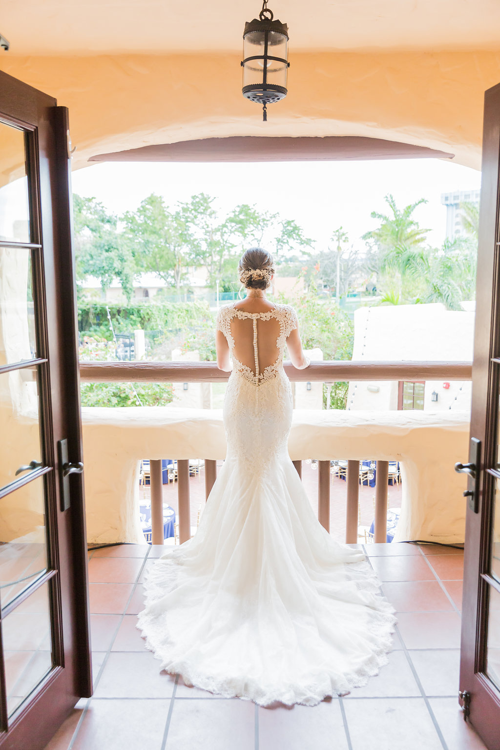 The bride looked over her guests from the Curtiss Mansion balcony in her lace open back, beaded and lace wedding dress with low undo and hair piece