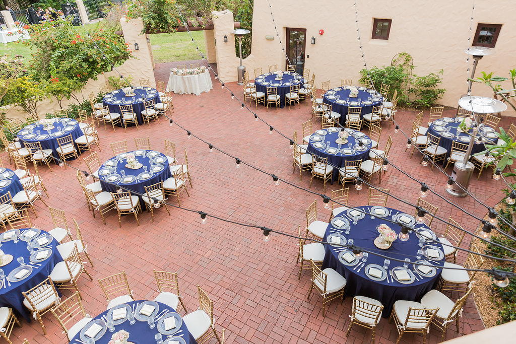 The Curtiss Mansion wedding had dinner in the courtyard with navy blue linens, gold beaded charger plates, gold chiavari chairs, and ivory seat cushions
