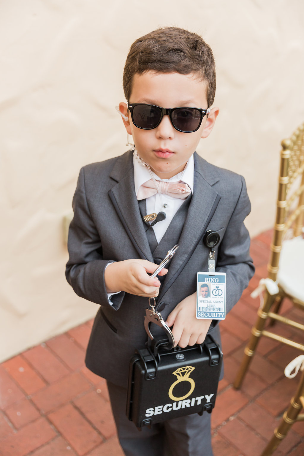 The ring bearer sported a ring security outfit complete with special agent sunglasses, an ear piece, handcuffs, and ring briefcase