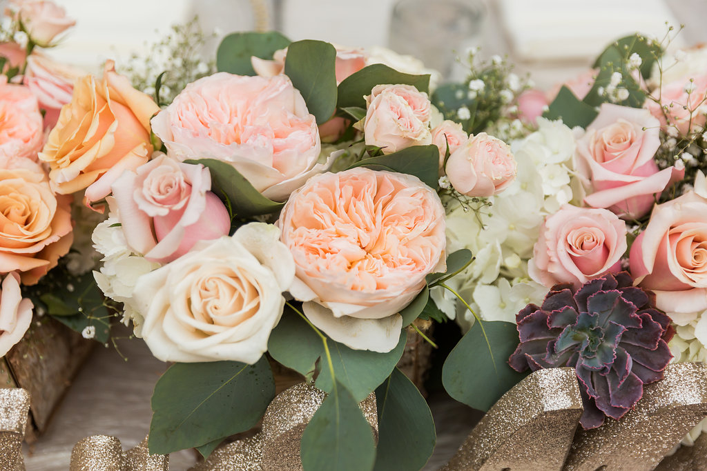 The centerpieces included coral, pink, blush, and ivory flowers of roses, garden roses, baby's breath, and succulents