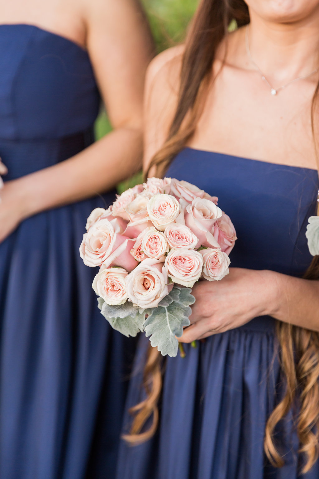 The bridesmaids wore navy blue and carried rose and dusty miller bouquets