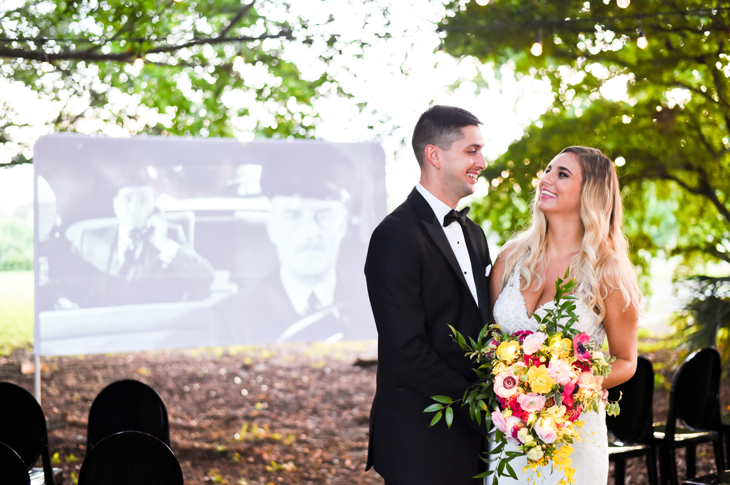 The bride and groom laugh as a movie plays on the projector screen behind them