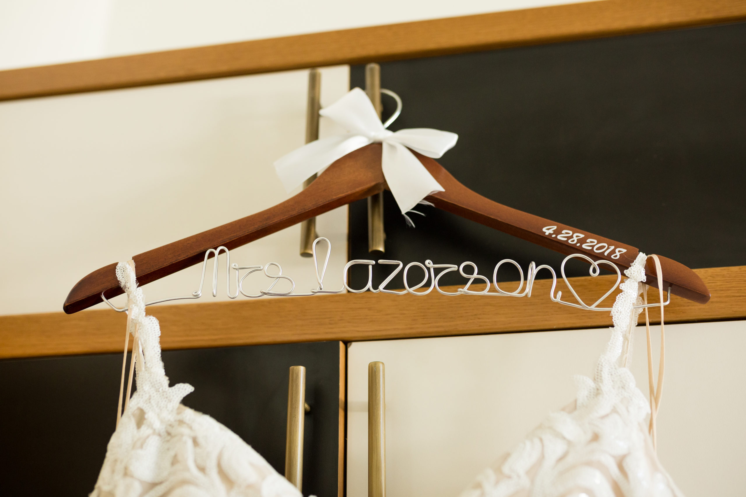 The bride's dress hung on a custom wire hanger with her name on it