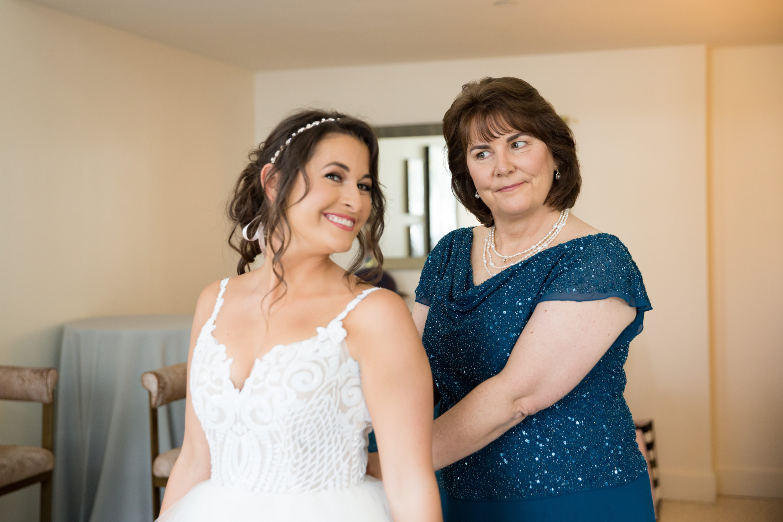 The bride's mom helps her into her wedding dress