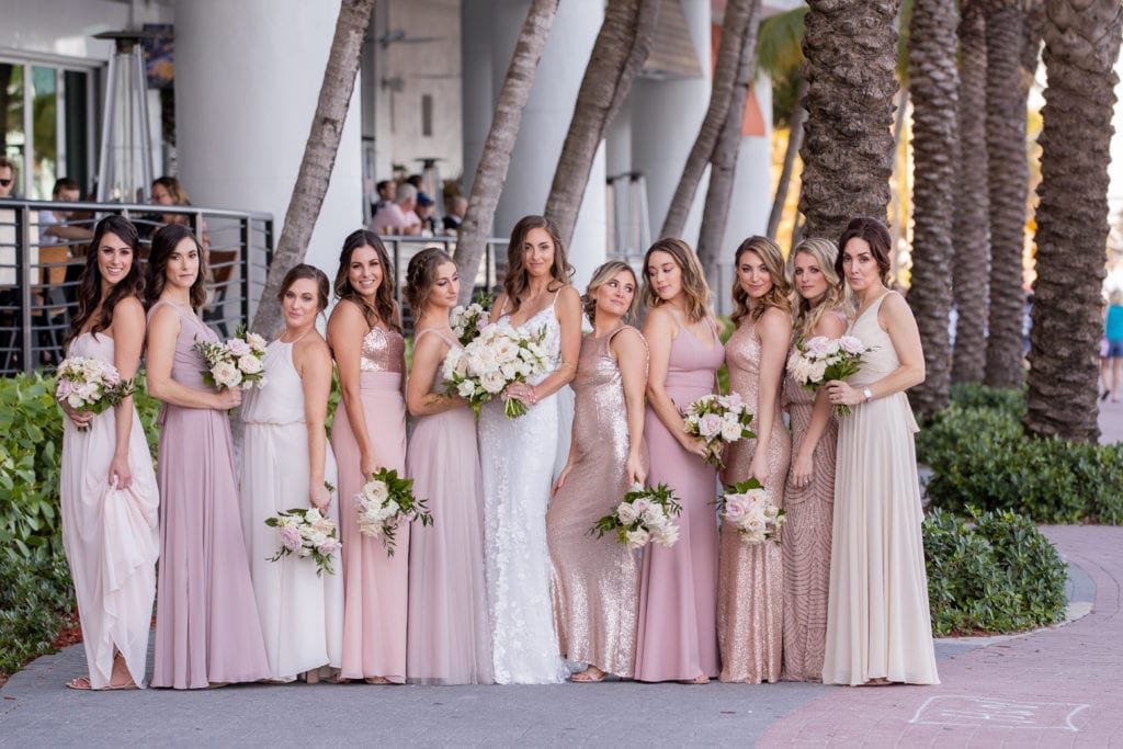 the bridesmaids strike a pose with the bride showcasing their blush, mauve, and champagne dresses