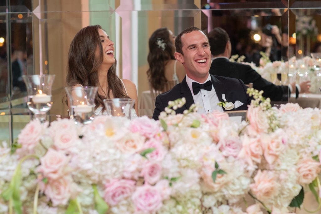 bride and groom laugh at their sweetheart table during toasts