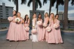 bridesmaids wear varying blush dresses and carry white and blush bouquets