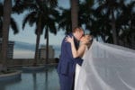 bride and groom kiss while her veil blows in the wind on the four seasons Miami wedding pool deck