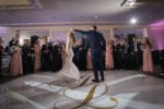 groom spins the bride during their first dance on a white vinyl wrapped dance floor