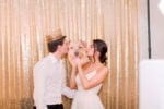 bride and groom kiss a photo booth prop of their dog's head