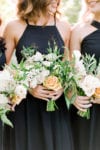 peach and ivory bouquets are held by bridesmaid wearing a black dress