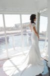 bride stands in her cap sleeved wedding gown in front of a floor mirror