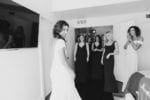 bride reveals her wedding dress to her adoring bridesmaids as they squeal and cheer with delight