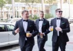 groom and groomsmen walk to the church with drinks in hand
