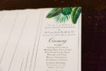 the wedding program features printed tropical leaves