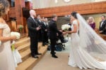 the groom shakes the father of the bride's hand as she walks down the aisle to him