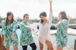 bride and bridesmaids dance in their robes on the boat dock