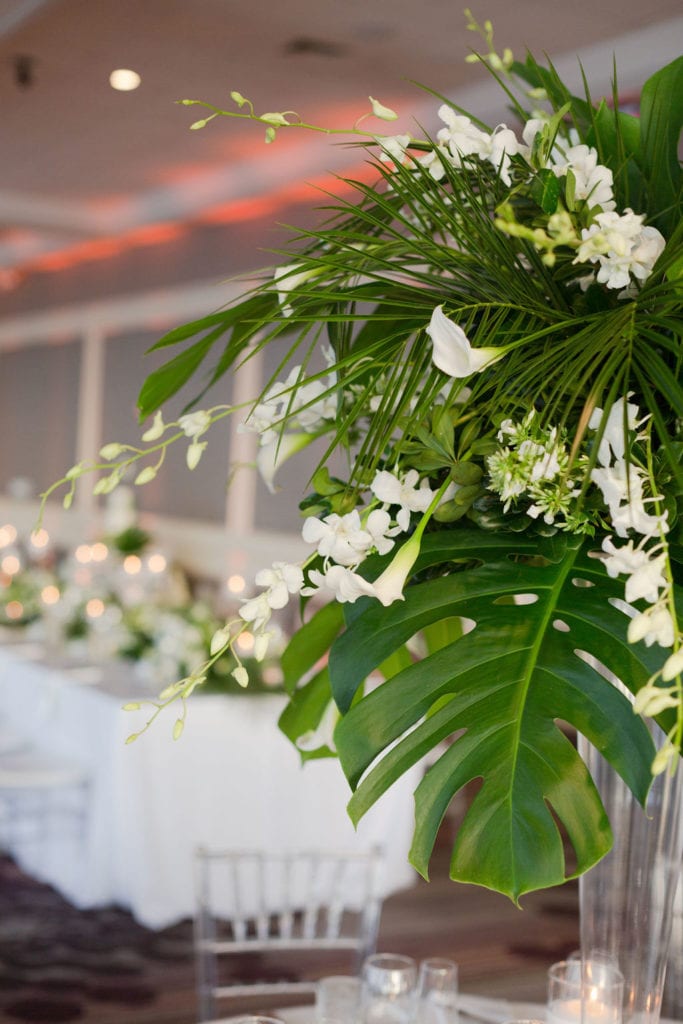 Beautiful green floral arrangements of monstera leaves, orchids, and white accents at The Rusty Pelican, planned by Oh My Occasions 