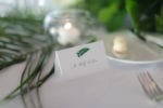 a tropical leaf accents a tented place card with guest's name