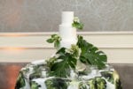 a four tier white wedding cake adorned with large palm leaves on top of a palm leaf tropical linen
