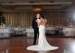 bride and groom embrace each other in front of their wedding guest tables in the Rusty Pelican ballroom
