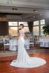 The bride smiles over her shoulder in the Rusty Pelican ballroom, with her dress train flared out