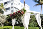 a draped and floral chuppah ceremony structure on the lawn of LaPlaya Naples