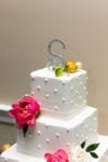 a bedazzled wedding cake topper on a buttercream dotted cake