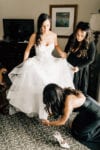 bride's sisters help her into her wedding shoes