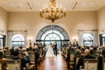 bride and groom stand at the altar in the Frenchman's Reserve dining room under a large chandelier