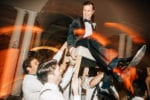 the groom smiles downward at his groomsmen during the Hora lift