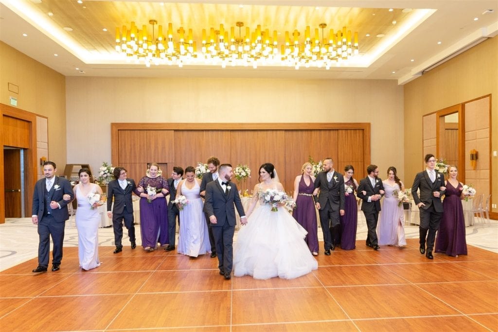 bride and groom walk with their wedding party in the ballroom of Conrad Ft. Lauderdale