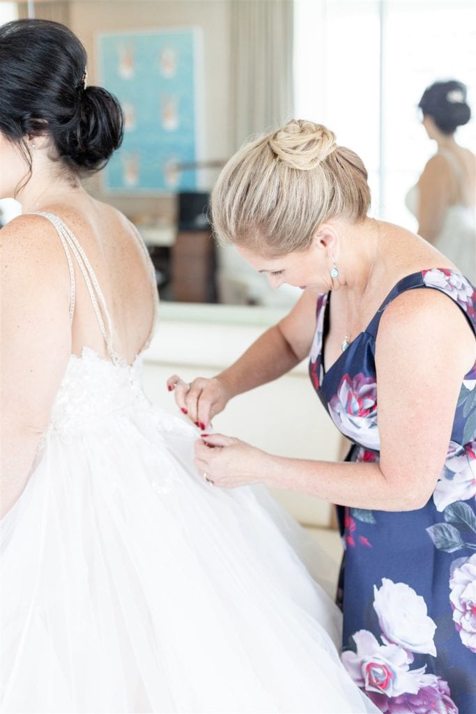 The last finishing touches of putting on the bride's dress at The Conrad Fort Lauderdale Beach, wedding planned by Oh My Occasions