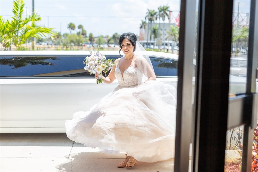 The bride stepping out of the limousine and into the church for the ceremony at The Conrad Fort Lauderdale Beach, wedding planned by Oh My Occasions