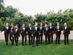 groomsmen in black tuxedos walk on the terrace smiling at the miami beach edition