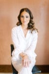 the bride wears ruffle sleeve pajamas in white with simple and elegant loose curl wedding hairstyle by marz makeup and hair