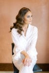 the bride wears ruffle sleeve pajamas in white with simple and elegant loose curl wedding hairstyle by marz makeup and hair