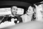 bride and groom laugh in their bridal car